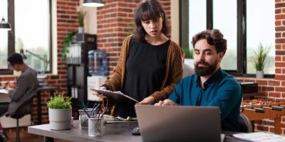 Executive managers analyzing papers with marketing statistics discussing company strategy while working at business collaboration in brick wall startup office. Businesspeople brainstorming ideas