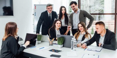 Staff meeting. Group of   young modern people in smart casual wear discussing something while working in the creative office . Business time..